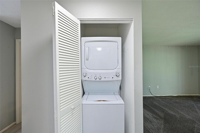 laundry area with stacked washer / dryer and dark colored carpet