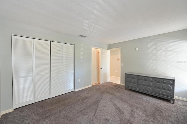 unfurnished bedroom with dark carpet, a closet, and a textured ceiling