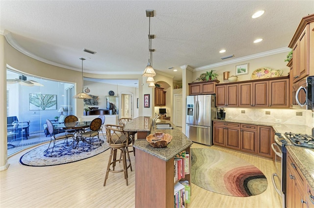 7215 Treymore Ct, Sarasota, FL 34243 - kitchen with a kitchen island, pendant lighting, backsplash, stainless steel appliances, and crown molding
