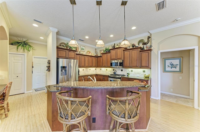 7215 Treymore Ct, Sarasota, FL 34243 - kitchen featuring stainless steel appliances, decorative light fixtures, a kitchen island with sink, and a breakfast bar area