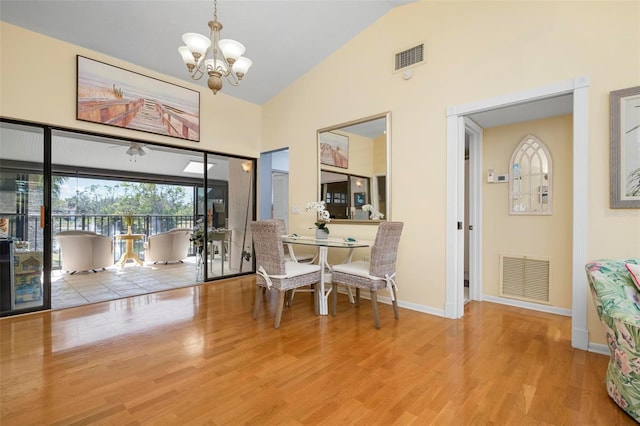 dining room featuring an inviting chandelier, light hardwood / wood-style flooring, and high vaulted ceiling