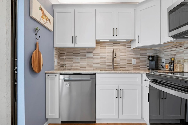 kitchen featuring light stone counters, stainless steel appliances, sink, and white cabinets