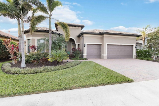 mediterranean / spanish house featuring a garage and a front yard