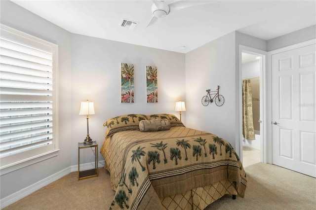 bedroom with ensuite bath, light colored carpet, and ceiling fan