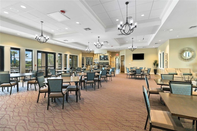 dining space featuring ornamental molding, a chandelier, a raised ceiling, and light carpet