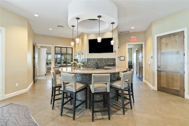 kitchen featuring decorative light fixtures, backsplash, a kitchen breakfast bar, light tile patterned floors, and kitchen peninsula