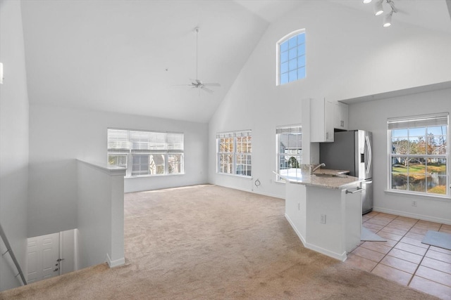 kitchen featuring a breakfast bar, stainless steel fridge with ice dispenser, light carpet, kitchen peninsula, and white cabinets