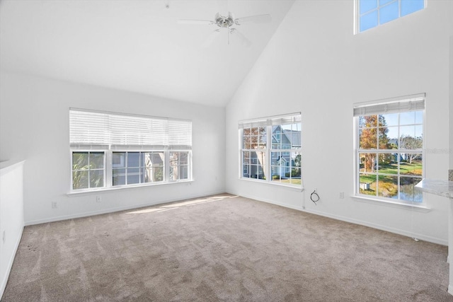 unfurnished living room with a wealth of natural light, high vaulted ceiling, and carpet