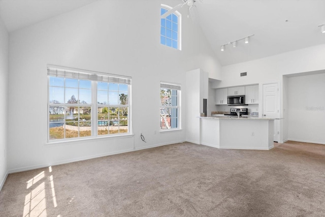 unfurnished living room featuring light carpet and high vaulted ceiling