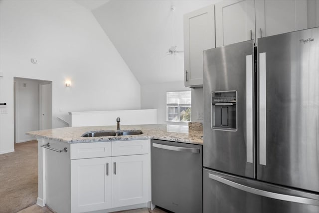 kitchen with sink, white cabinetry, light stone counters, kitchen peninsula, and stainless steel appliances