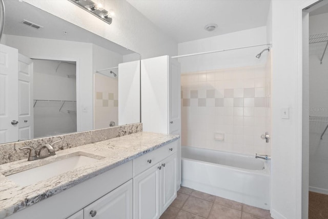 bathroom with tile patterned floors, vanity, and tiled shower / bath