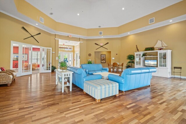 living room featuring a high ceiling, light hardwood / wood-style floors, and french doors