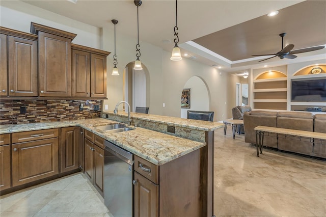 kitchen featuring built in features, sink, hanging light fixtures, stainless steel dishwasher, and kitchen peninsula