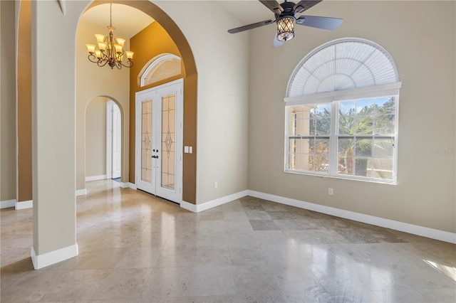 foyer with ceiling fan with notable chandelier and a high ceiling