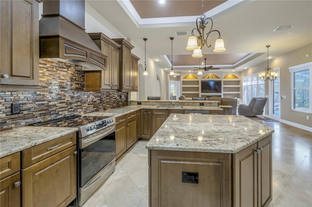 kitchen with custom exhaust hood, decorative light fixtures, a tray ceiling, a kitchen island, and electric stove