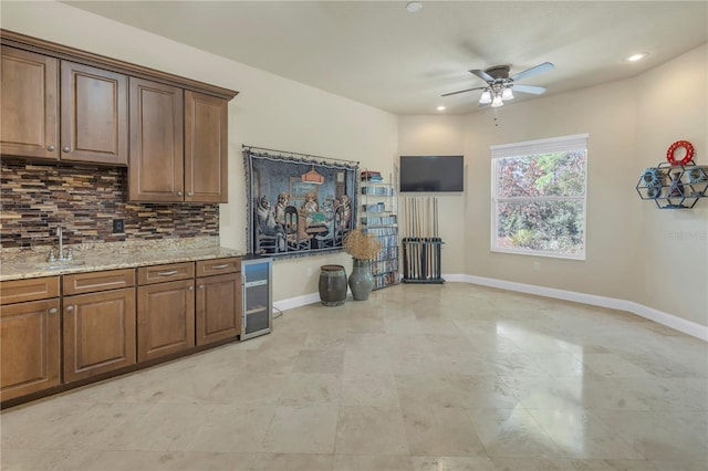 kitchen with backsplash, light stone countertops, sink, and ceiling fan