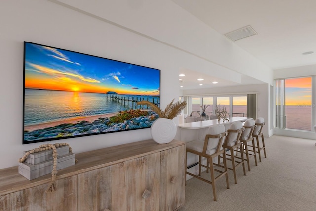 bar featuring light colored carpet and a water view