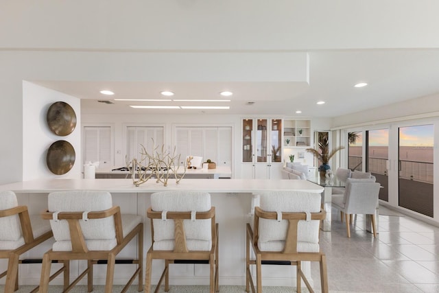 kitchen featuring light tile patterned floors, kitchen peninsula, a kitchen breakfast bar, and french doors