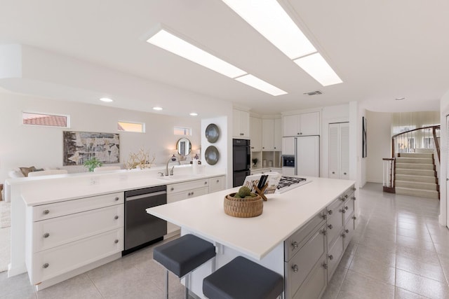 kitchen featuring a kitchen bar, white cabinetry, kitchen peninsula, a kitchen island, and stainless steel appliances