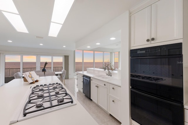 kitchen with sink, white cabinetry, a skylight, a water view, and black appliances