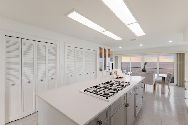 kitchen featuring white gas stovetop, light tile patterned flooring, and a kitchen island