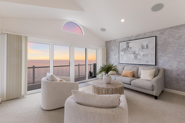 carpeted living room with high vaulted ceiling and a water view