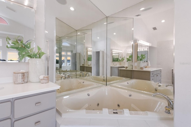 bathroom with vanity, a relaxing tiled tub, and vaulted ceiling