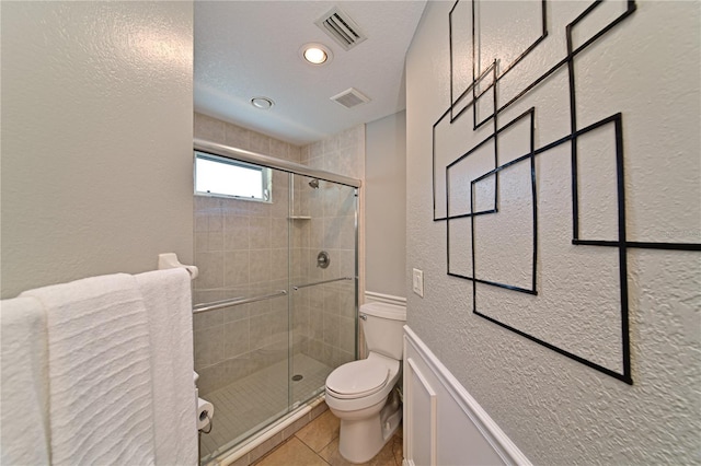 bathroom featuring tile patterned floors, toilet, and an enclosed shower