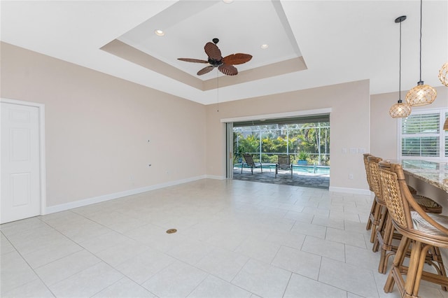 interior space with light tile patterned floors, ceiling fan, and a tray ceiling