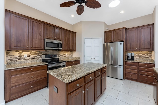 kitchen featuring stainless steel appliances, a kitchen island, light tile patterned floors, and light stone counters