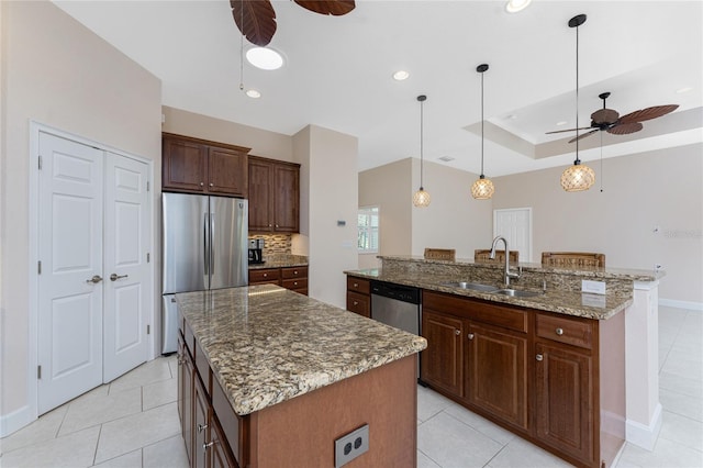 kitchen featuring pendant lighting, sink, appliances with stainless steel finishes, and a center island with sink