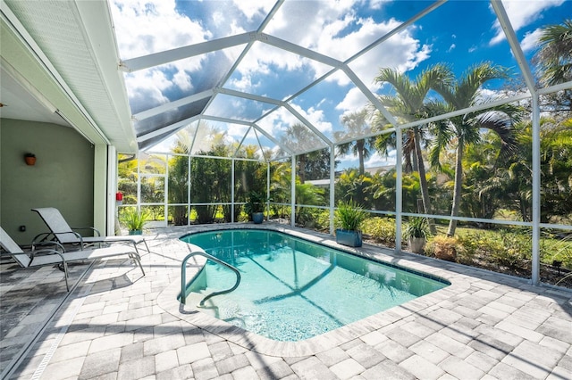 view of swimming pool with a patio area and glass enclosure