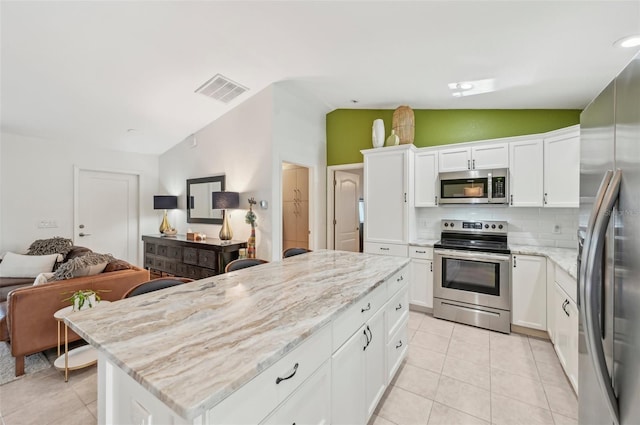 kitchen with lofted ceiling, white cabinetry, tasteful backsplash, and stainless steel appliances