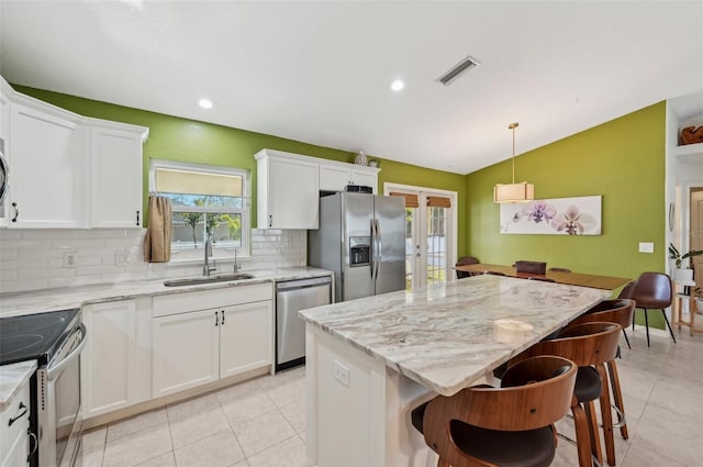 kitchen with french doors, lofted ceiling, sink, appliances with stainless steel finishes, and white cabinets