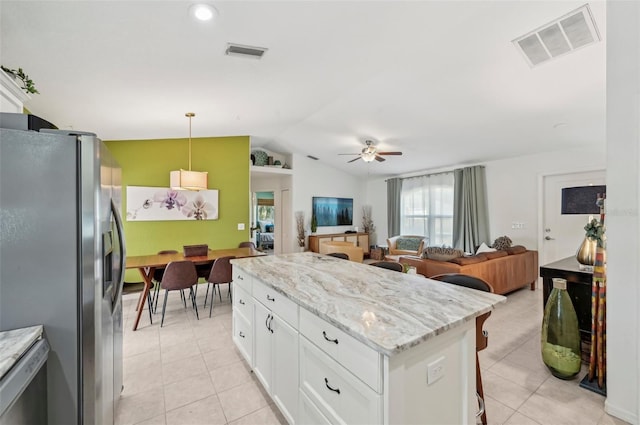 kitchen with white cabinetry, stainless steel fridge, light stone counters, and decorative light fixtures