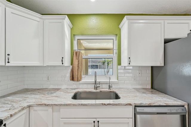 kitchen featuring sink, stainless steel dishwasher, white cabinets, and light stone counters