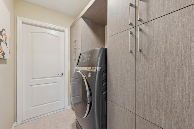 washroom with washer / clothes dryer, light tile patterned floors, and cabinets