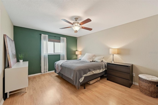 bedroom with light wood-type flooring, a textured ceiling, and ceiling fan