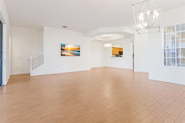 unfurnished living room with an inviting chandelier and light hardwood / wood-style floors