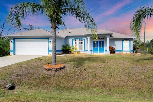 ranch-style house featuring a garage and a yard