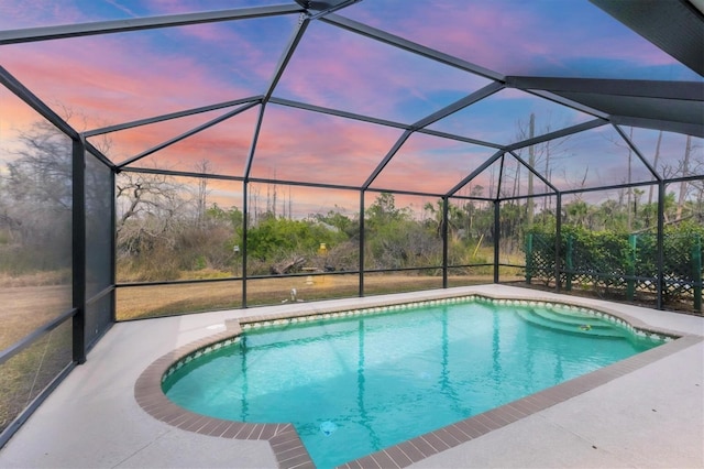 pool at dusk with a lanai and a patio area