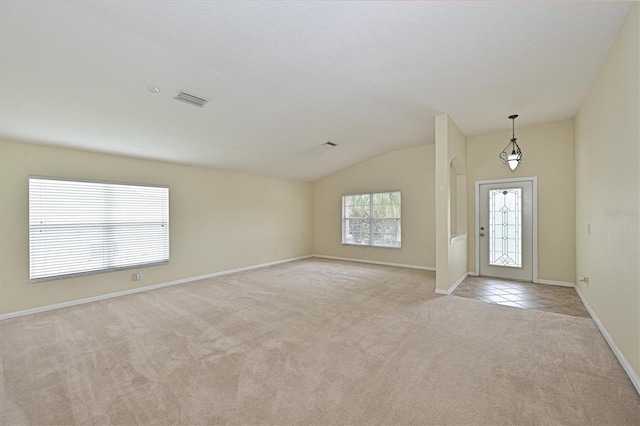 carpeted entrance foyer featuring vaulted ceiling and a textured ceiling