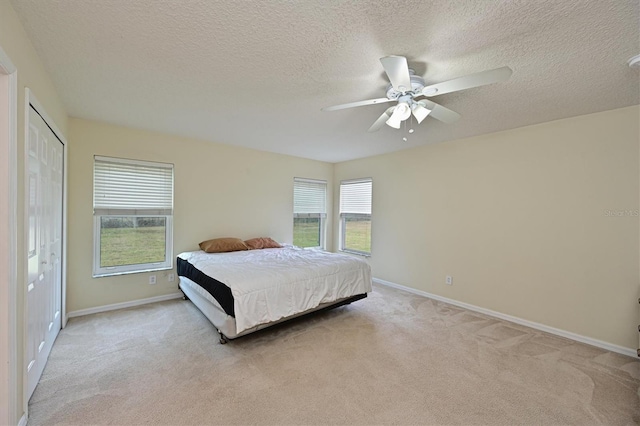 carpeted bedroom with a textured ceiling, a closet, and ceiling fan