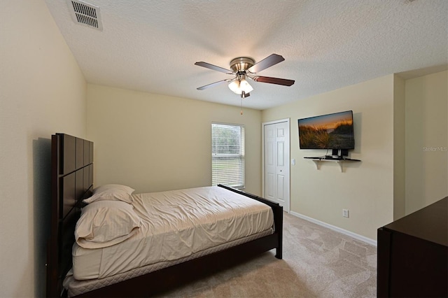 bedroom with light carpet, a textured ceiling, a closet, and ceiling fan