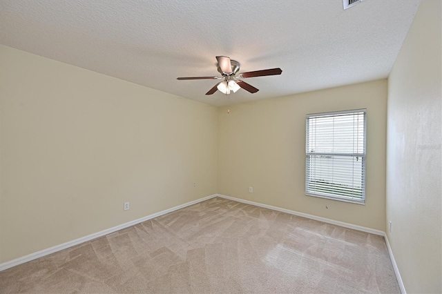 spare room featuring ceiling fan, light carpet, and a textured ceiling