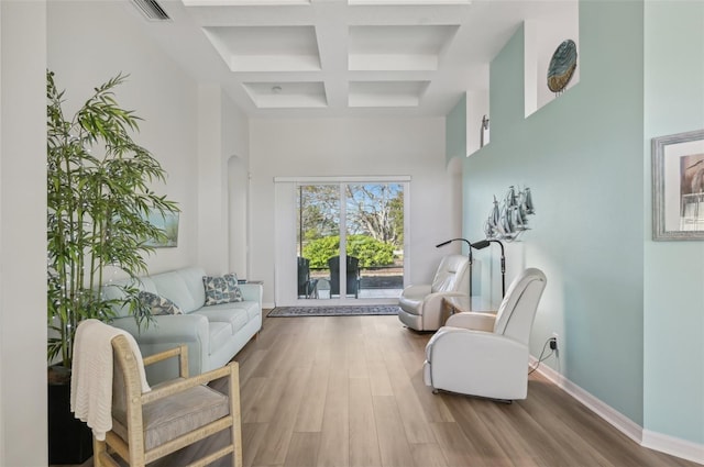 sitting room with hardwood / wood-style flooring, a towering ceiling, coffered ceiling, and beamed ceiling