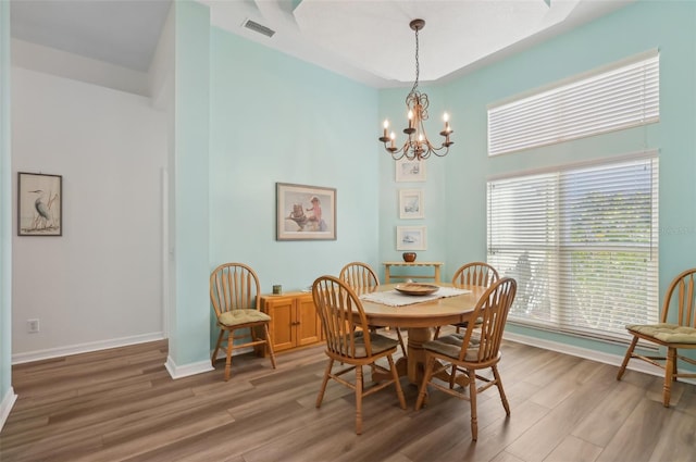 dining room with a notable chandelier, plenty of natural light, and wood-type flooring