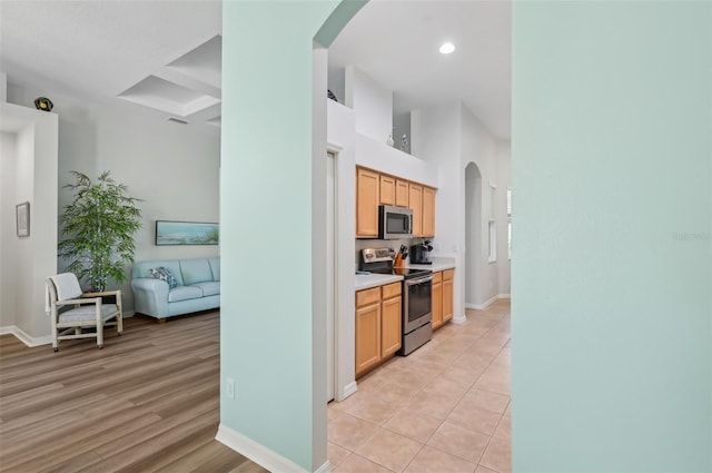 kitchen featuring stainless steel appliances, beam ceiling, light tile patterned floors, and light brown cabinets