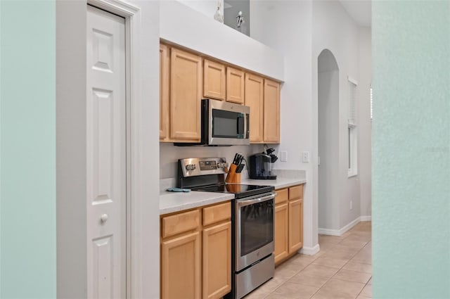 kitchen with light brown cabinetry, light tile patterned floors, and appliances with stainless steel finishes