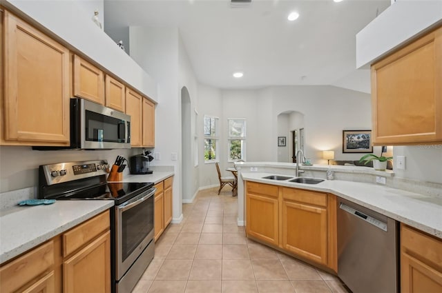 kitchen featuring appliances with stainless steel finishes, sink, light tile patterned floors, kitchen peninsula, and light stone countertops